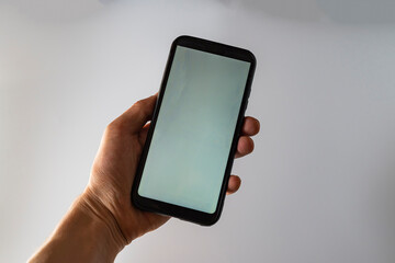 Woman hand holds smartphone with white screen. Female hand demonstrating new smartphone with blank screen
