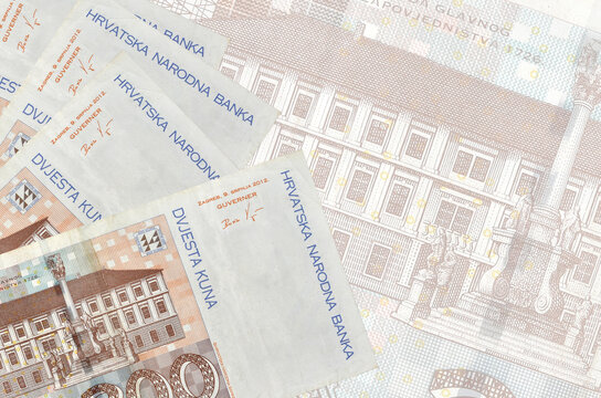 200 Croatian kuna bills lies in stack on background of big semi-transparent banknote. Abstract business background