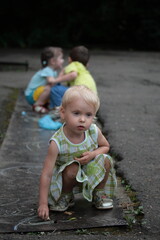 Little girl draws with chalk on asphalt