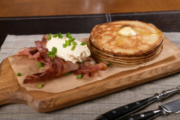 Pancakes with bacon and cheese on a wooden board 