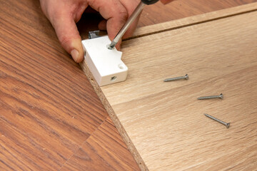 Assembling furniture, close-up of a tool in hand. The mounting screw is screwed into the hole in...