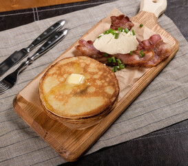 Pancakes with bacon and cheese on a wooden board 