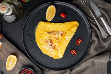 Spanish omelette, fresh red chilli, brown and white crabmeat, lemon, Cheddar cheese, eggs fried, on plate, on black wooden table background, top view flat lay - obrazy, fototapety, plakaty