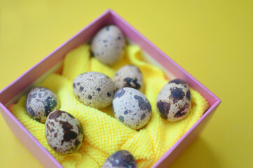 Easter gift box with quail eggs. Close-up photo on yellow background. Easter.