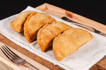 Four empanadas in a row on top of a wooden table