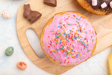 Homemade glazed and decorated easter pies with chocolate eggs and rabbits on a white concrete background. top view, close up.