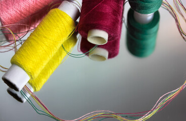 Multicolored threads in the coils are reflected on the surface of the mirror. Sewing and needlework
