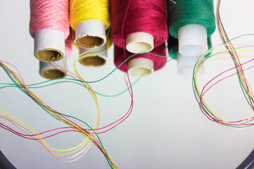 Multicolored threads in the coils are reflected on the surface of the mirror. Sewing and needlework
