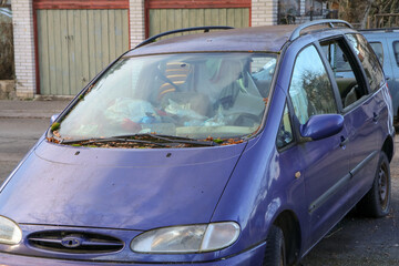 Fototapeta premium The detail of an abandoned broken car, now a wreck with damaged or broken windows and full of rubbish or waste. Occupies a parking place for the others. 
