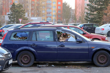 The detail of an abandoned broken car, now a wreck with damaged or broken windows and full of rubbish or waste. Occupies a parking place for the others.   - obrazy, fototapety, plakaty