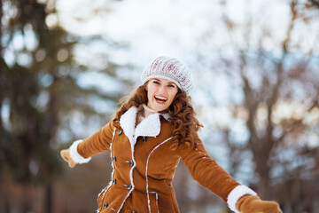 happy modern female rejoicing outside in city park in winter