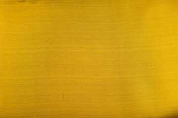 Fragment of smooth yellow and green tissue. Top view, synthetic textile background.