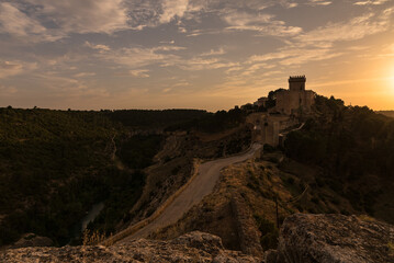 Landscape with a road toward the fortified city of Alarcon with the castle on top of the hill at sunset, Cuenca, Spain