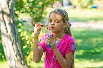 Girl inflates soap bubbles on a bright sunny day in the park