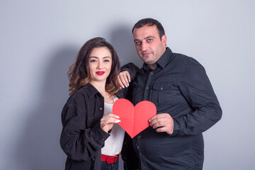 Young happy couple in love holding a red paper heart.