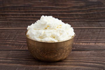 Freshly Churned White Butter Also Known As Safed Makhan Malai Or Homemade Makkhan In India Is Used To Prepare Desi Ghee In Brass Bowl. Isolated On Brown Wooden Background With Copy Space For Text