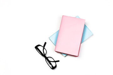 Pink and blue books and glasses on white isolated background. Education and freelancer work minimal concept with blank book cover, copy space for text. Back to school or office Flat lay, top view