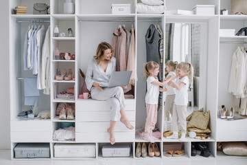 Young mother with her twin daughters choose things online in the comfort dressing room