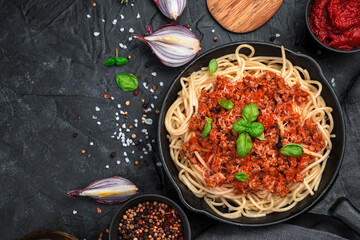 Culinary background with pasta and tomato sauce and fresh herbs on a black concrete background. The concept of cooking.