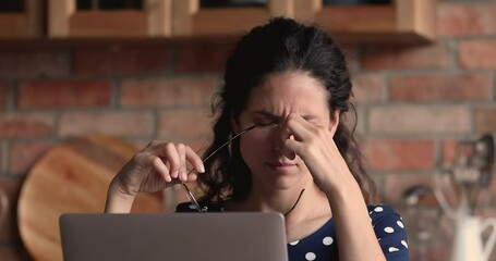 Close up tired after long laptop usage overworked woman stretch stiff neck take off glasses feel discomfort of sore eyes. Device overuse, sedentary lifestyle, negative influence of modern tech concept