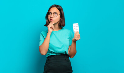 young hispanic woman thinking, feeling doubtful and confused, with different options, wondering...