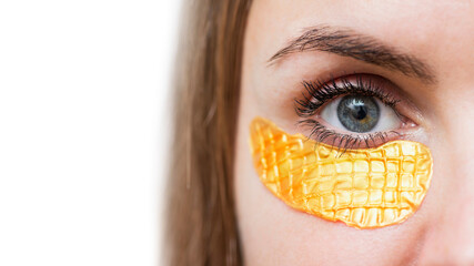 Close-up of a girl with golden patches under eyes. Mask for skin under the eyes against wrinkles and fatigue. Bags under the eyes and bruises, rejuvenating mask