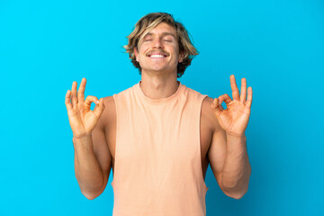 Handsome blonde man isolated on blue background in zen pose