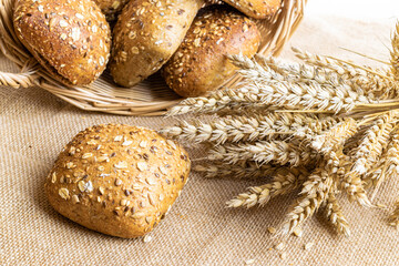 Rye bread isolated. Bakery with crusty loaves and crumbs. Fresh loaf of rustic traditional bread with wheat grain ear or spike plant on natural cotton background. Bio ingredients, healthy with seeds.