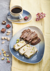 traditional arabic sweets sesame halva with chocolate and pistachio and a cup of coffee on a gray concrete background. side view, close up.
