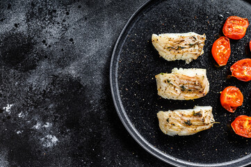 Baked cod fish fillet with spice.  Black background. Top view. Copy space