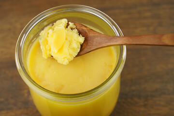  Homemade ghee in jar and wooden spoon .   Ghee is purified butter. 
