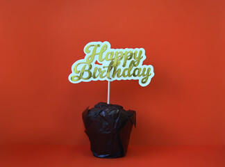 Chocolate cupcake with greeting sign close-up on red background - Happy birthday / Holiday card