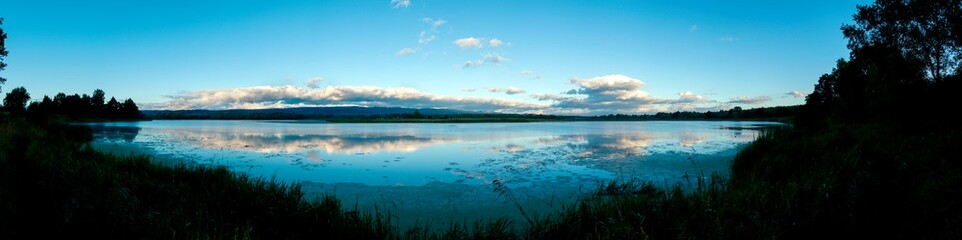 fishing pole with beautiful lake, mountains, forest and steel sky background. Fishing tool and sport concept