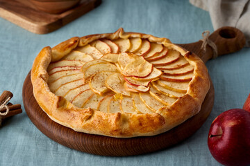 Apple pie, galette with fruits, sweet pastries on blue tablecloth, sweet crostata on cutting wooden...