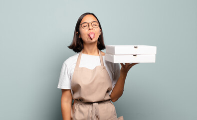 young hispanic woman with cheerful, carefree, rebellious attitude, joking and sticking tongue out,...