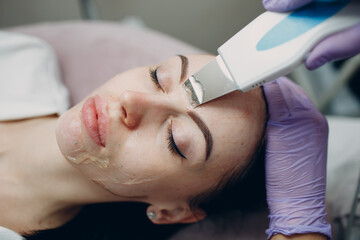 Obraz na płótnie Canvas Woman receiving cleansing therapy with a professional ultrasonic equipment in cosmetology beauty spa