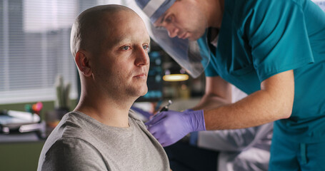 Bald man speaking with oncologist during vaccination