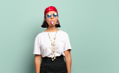 young latin woman with cheerful, carefree, rebellious attitude, joking and sticking tongue out,...