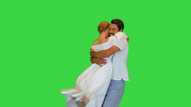 Young couple is running to each other, hug and spin on a Green Screen, Chroma Key.