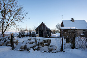 a lonely farmstead in the Latvian countryside in Vidzeme where a farm is in the foreground then behind it and you can see snow-covered roofs