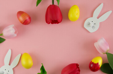 Tulips, Easter eggs, wooden bunny on a pink background. Background for design. Easter design. Copy space.