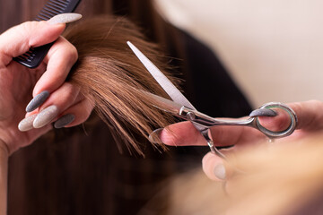 Naklejka premium Hairdresser hand with glitter nails holding scissors for haircut in hairdressing salon