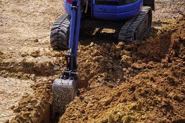 Digging a trench for the foundation. Ground in backhoe dump bucket for earthmoving works in...