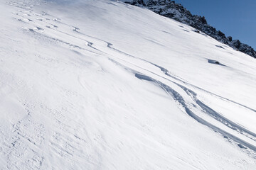 Fototapeta na wymiar Three fresh powder snow tracks on sunny winter slope