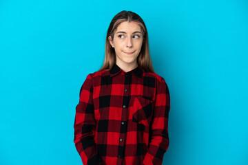 Fototapeta premium Young caucasian woman isolated on blue background having doubts while looking up