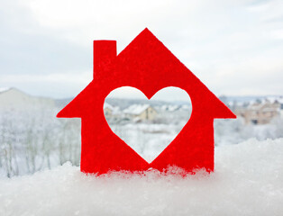 Small house cut out of red felt is standing in the snow. Heart-shaped hole is cut instead of a...