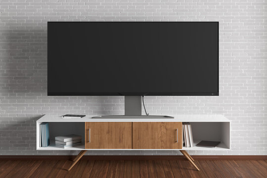 TV Wide Screen On The TV Stand Near White Brick Wall In Living Room.