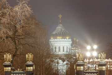 Obraz premium Moscow, Russia. Evening view of Christ The Saviour Cathedral framed by Alexander garden fence elements (two-headed eagles, Russian coat of arms). Shot in long focal length