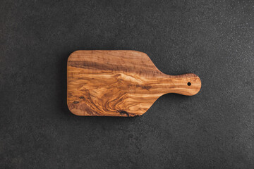 Empty olive wood kitchen board on black table. Top view.