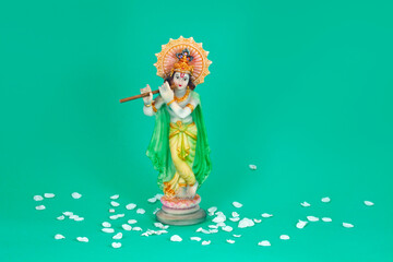 Hindu god Krishna. Statue with white petals on a green background.